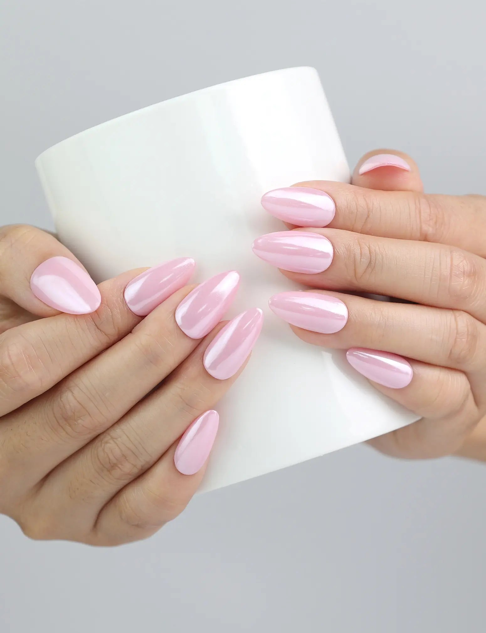 Hand holding a ceramic mug, featuring soft glossy pink press-on nails for a casual, polished vibe