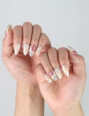 Side view of almond press-on nails with detailed red, white, and grey flower nail art and a natural glossy finish