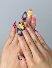 Hand model wearing almond-shaped press-on nails with glossy brown tones, leopard spots, and sculpted flowers