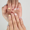 Hand wearing Rainbow Tips handmade press on nails, transparent base with bold colorful glitter tips for a cute and trendy look.