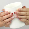 Hand holding a cup with Rainbow Tips handmade press on nails, blue, yellow, and red glitter tips adding a fun and lively accent.