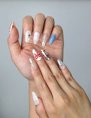 Close-up of Naillover’s handmade Singapore nails featuring detailed ribbon charms and sparkling rhinestones over checkered art