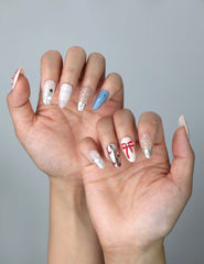 Side view of glossy almond nails with bold check patterns, red ribbon details, and a glam touch of crystals