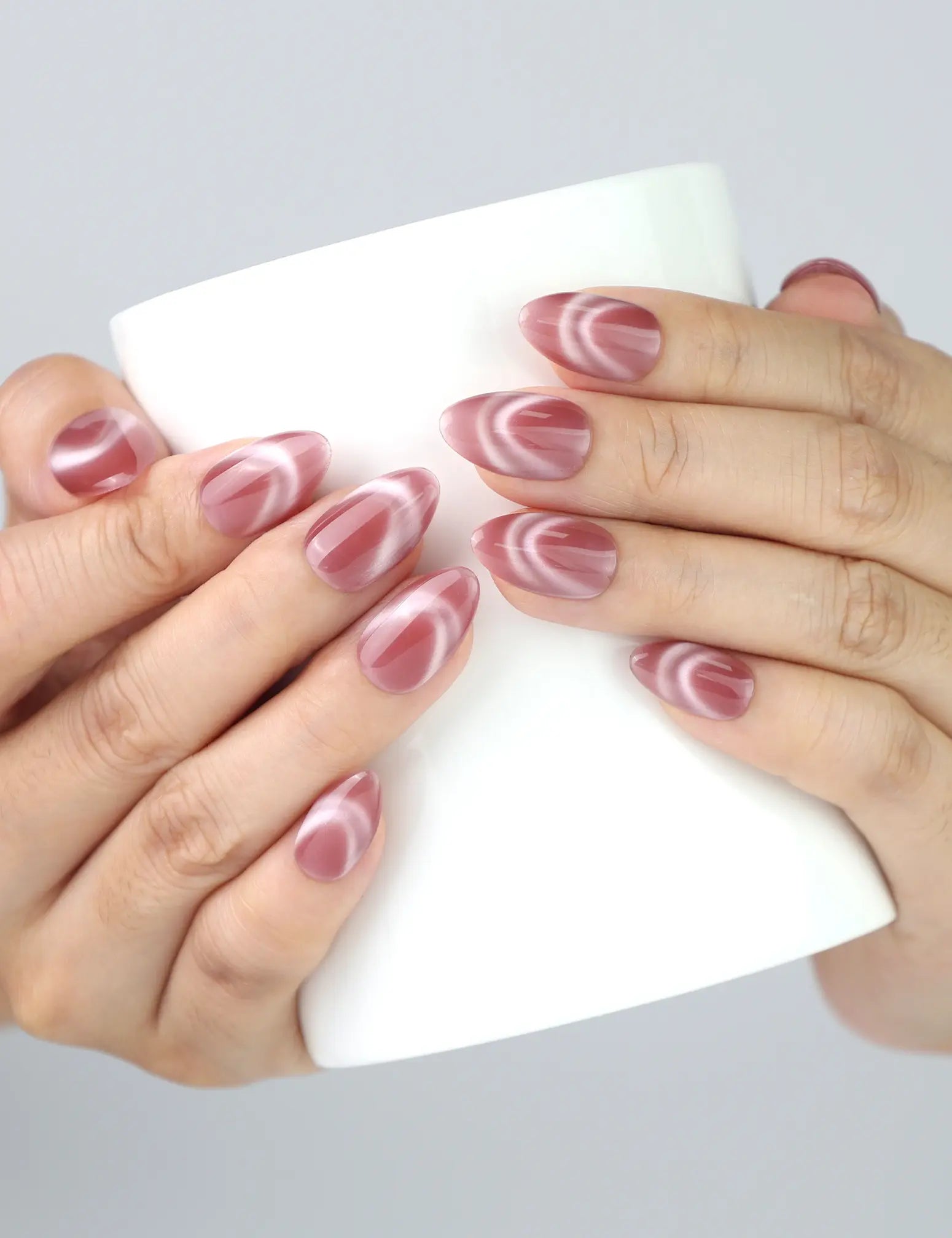 Hand holding a cup with Rosy French Glow nails by Naillover, showcasing pink French cat eye charm.