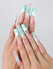 Hand gesture showcasing Singapore handmade long pipe press on nails with 3D floral art, ocean wave designs, and gold starfish accents by Naillover