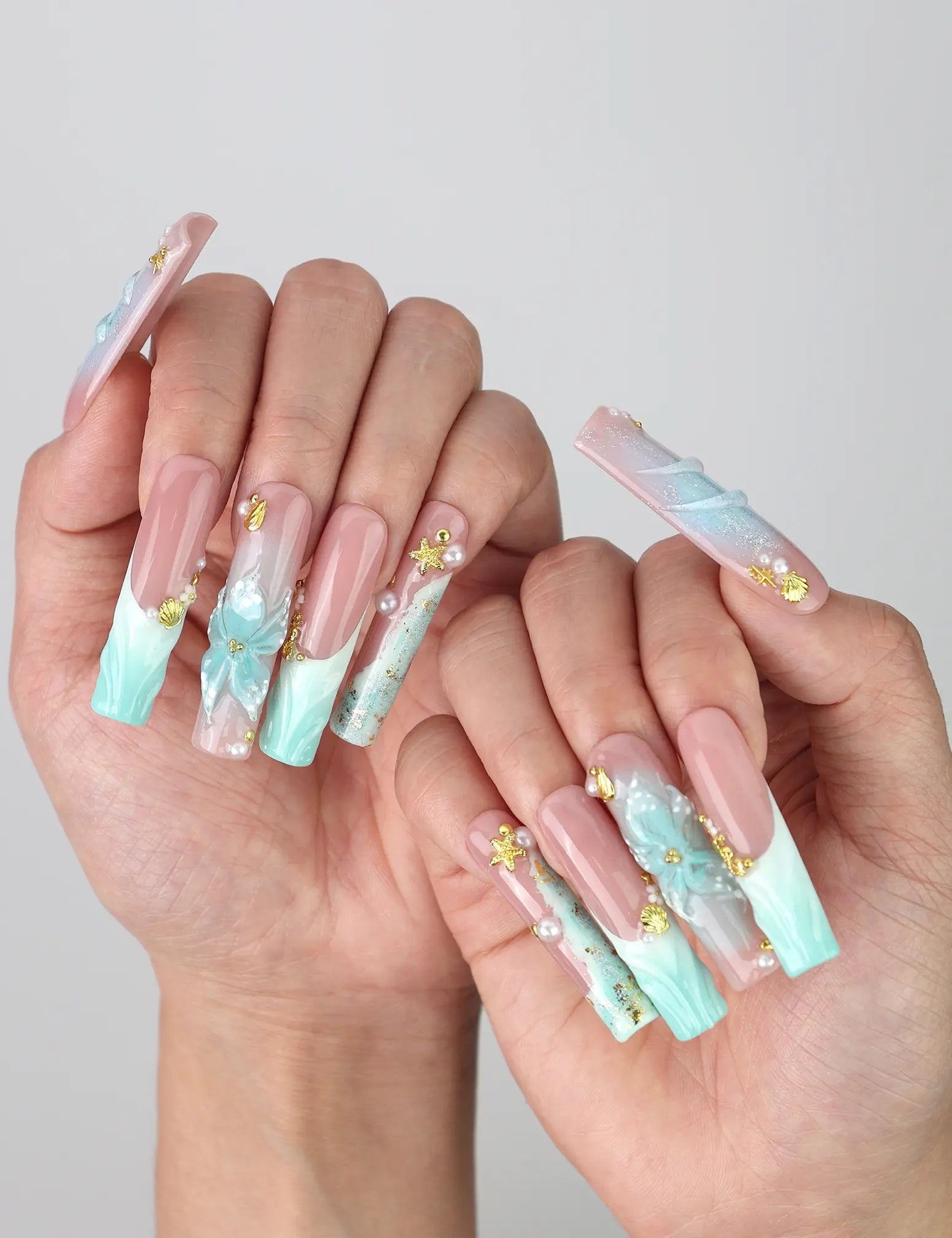 Pose highlighting sculptural pipe nails with sea wave textures, pastel blooms, and golden starfish details by Naillover