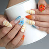 Hand holding a cup, showcasing Naillover’s colorful seaside-themed nails with sculpted seashell details