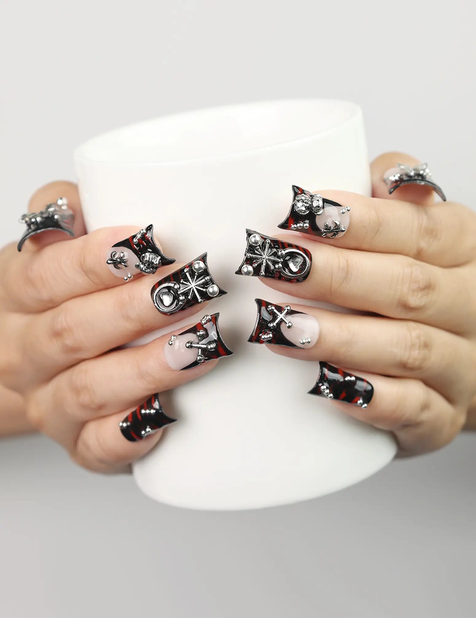 Model holding a coffee cup while wearing Shadow Forge Y2K metallic handmade press on nails by naillover