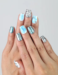 Hand model showing short coffin-shaped blue press-on nails with glossy metallic silver and 3D water droplet textures