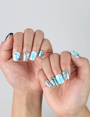 Side angle view of handmade Singapore blue coffin nails with chrome silver effects and liquid-style texture details