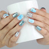 Hand holding a cup, displaying Naillover’s blue short coffin press-on nails with water droplet texture and metallic accents