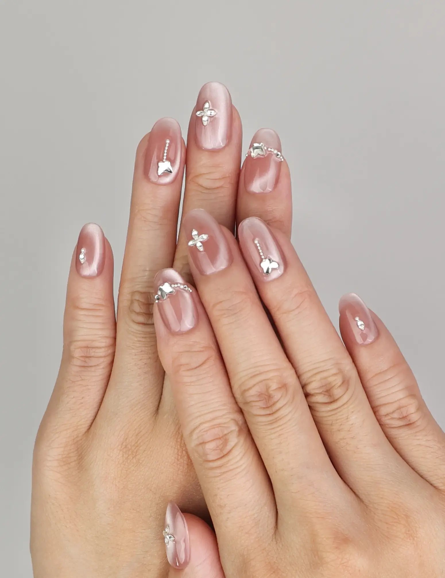 Hand wearing Naillover Silver Charm handmade press on nails with glossy cat eye finish and silver butterfly charms.