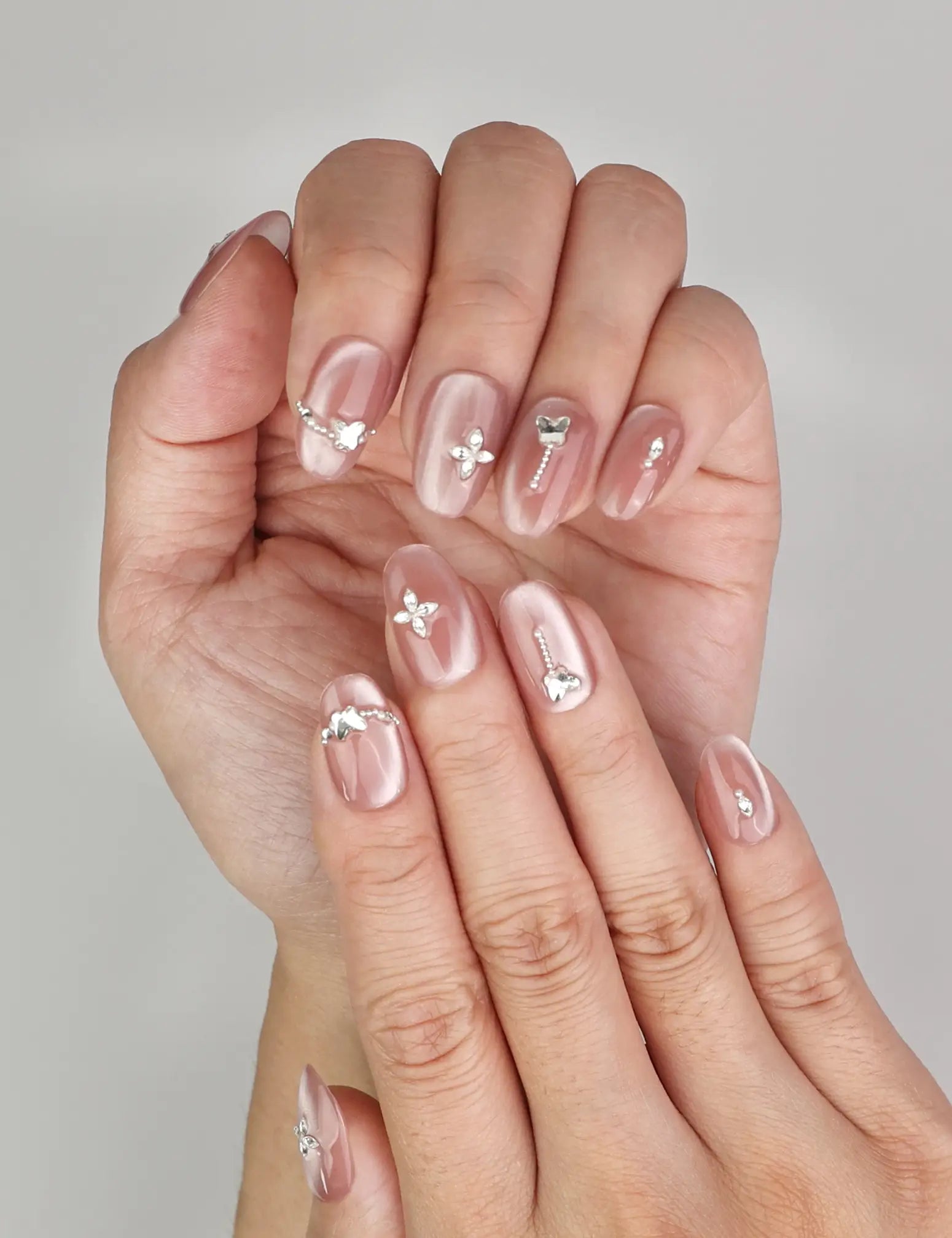 Close-up of Naillover Silver Charm Singapore press on nails, showing glossy cat eye shimmer and silver butterfly details.