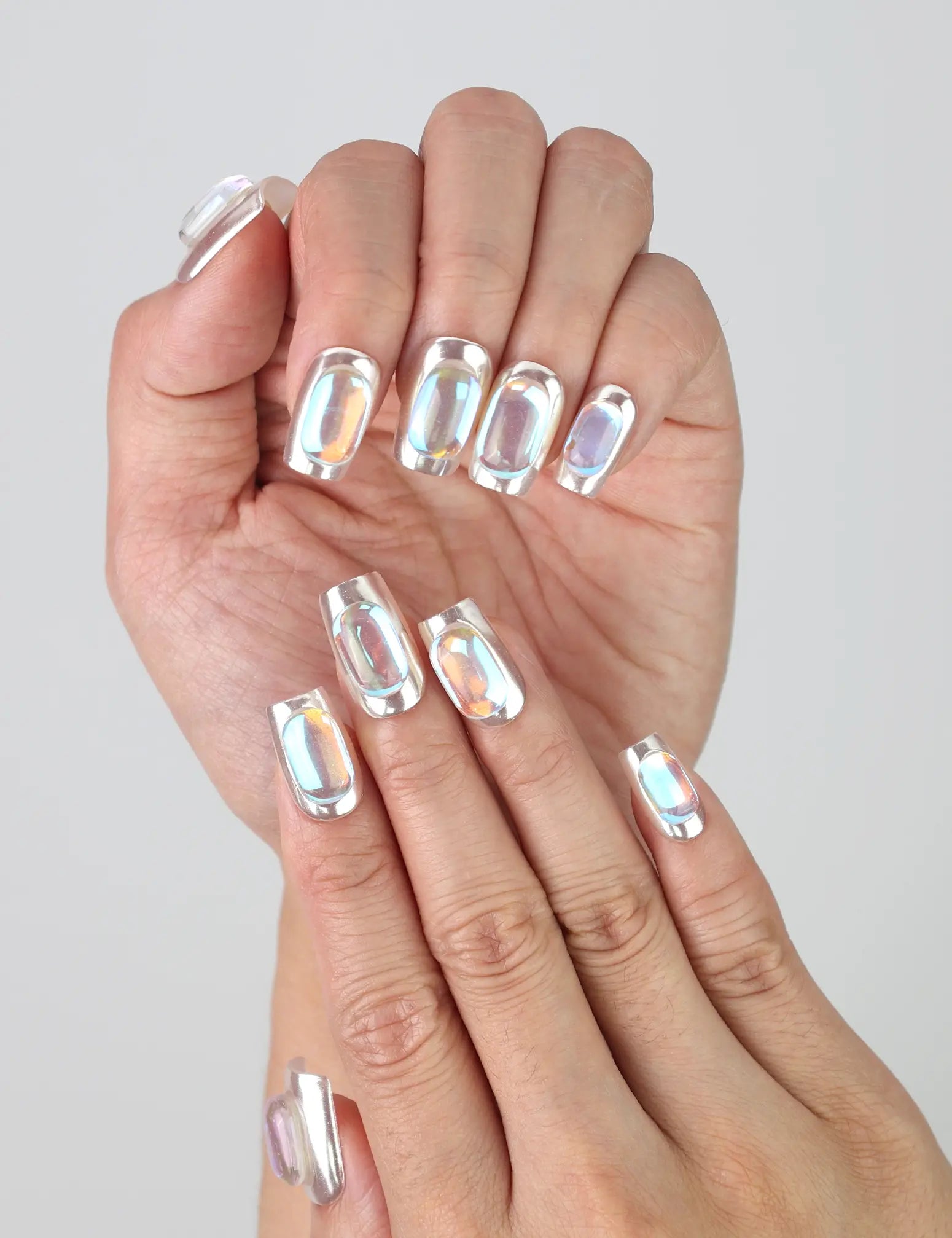 Fingers slightly curled to display Naillover’s Singapore handmade chrome silver nails with jewel embellishments