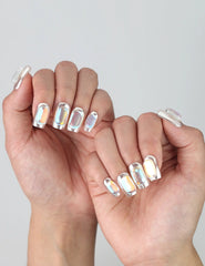 Close-up of hand wearing shiny silver press on nails with dimensional gem details for a futuristic look