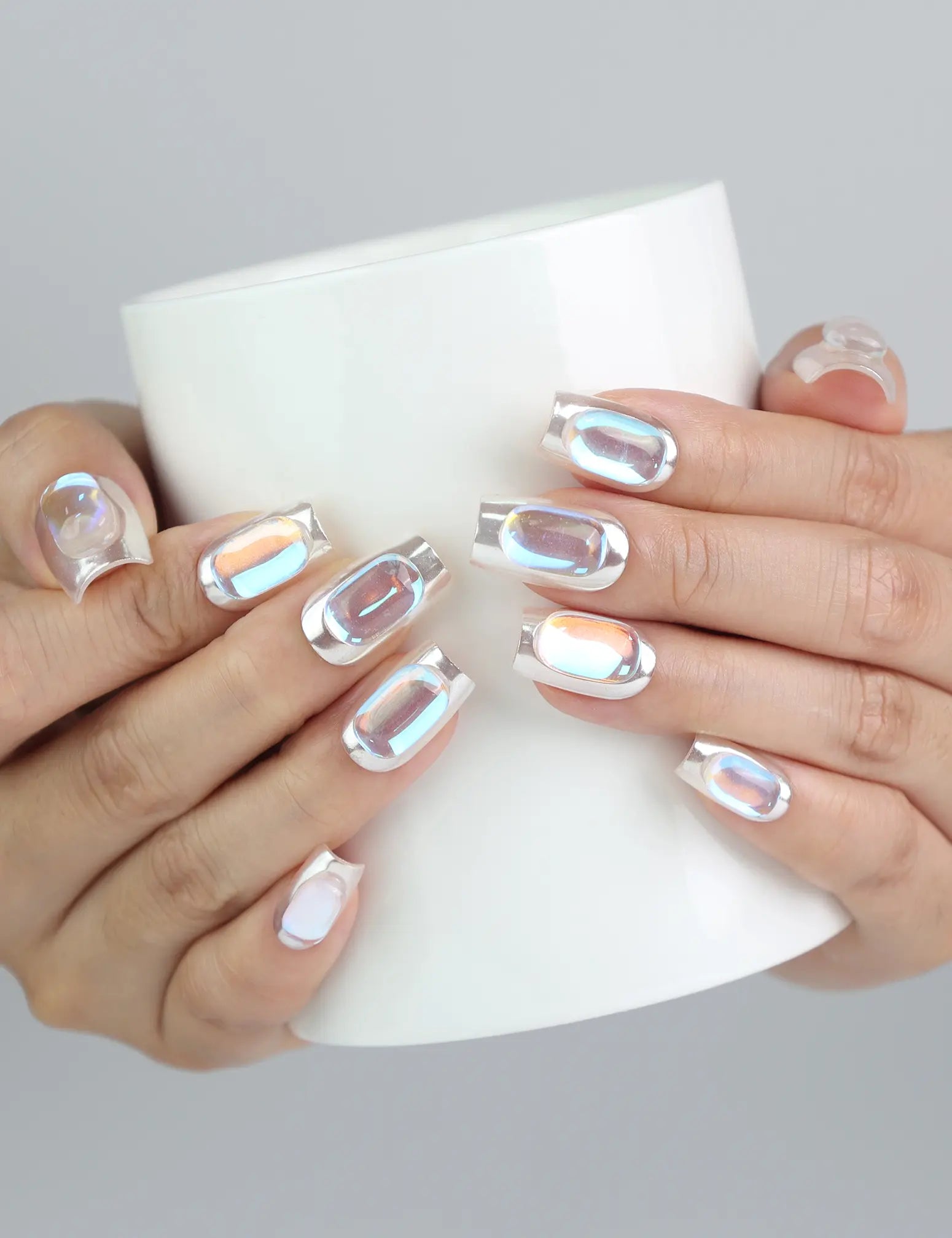 Hand holding a cup while flaunting metallic chrome medium press on nails with subtle gem sparkle by Naillover
