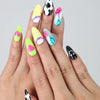 Hand with vibrant short almond nails featuring smiley faces and playful 3D hearts
