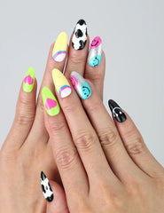 Hand with vibrant short almond nails featuring smiley faces and playful 3D hearts