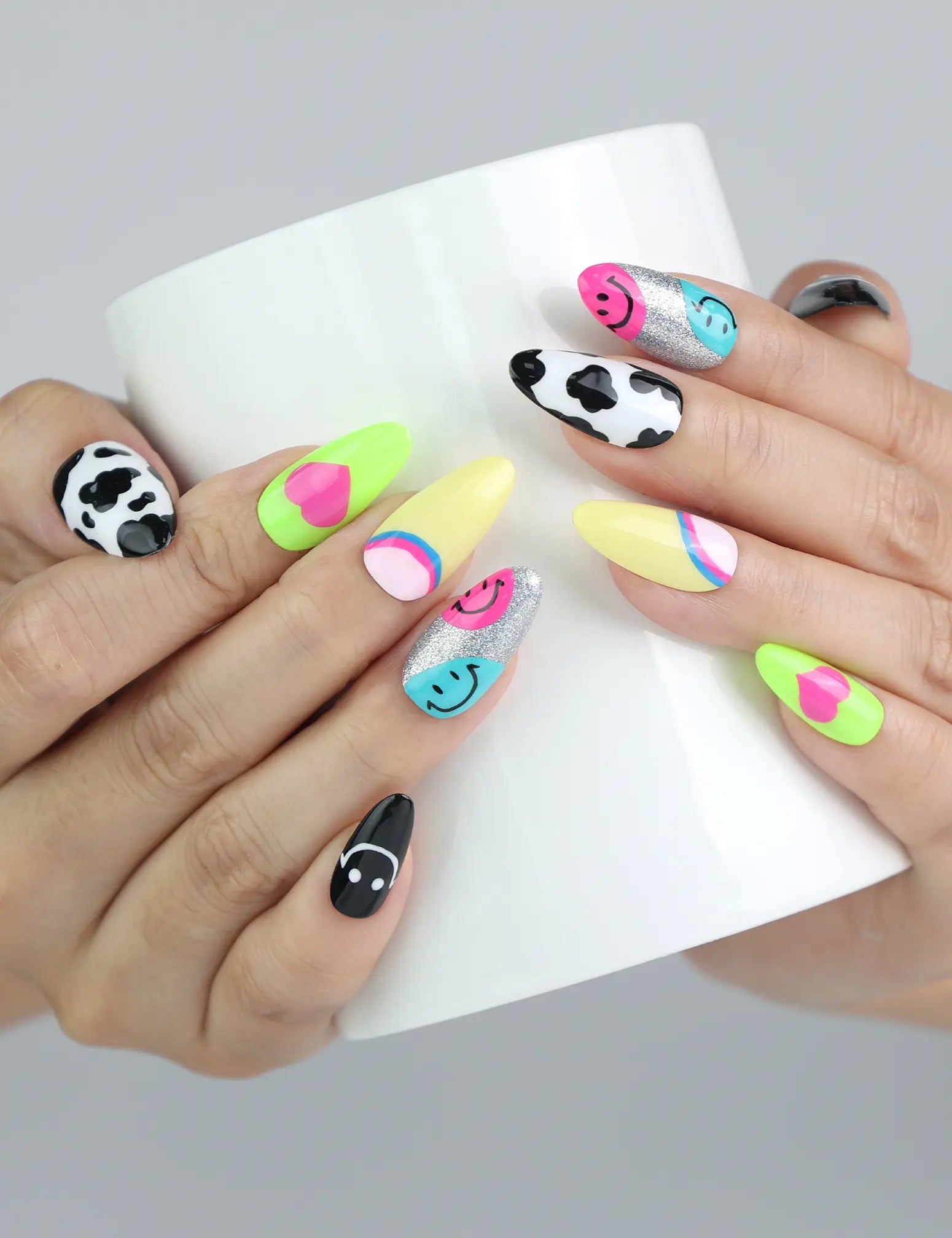 Hand holding a cup, showing playful press-on nails in bold colors and cute 3D accents