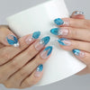 Hand holding a cup, showcasing Naillover mermaid-style press-on nails with pastel blue gradients and ocean textures