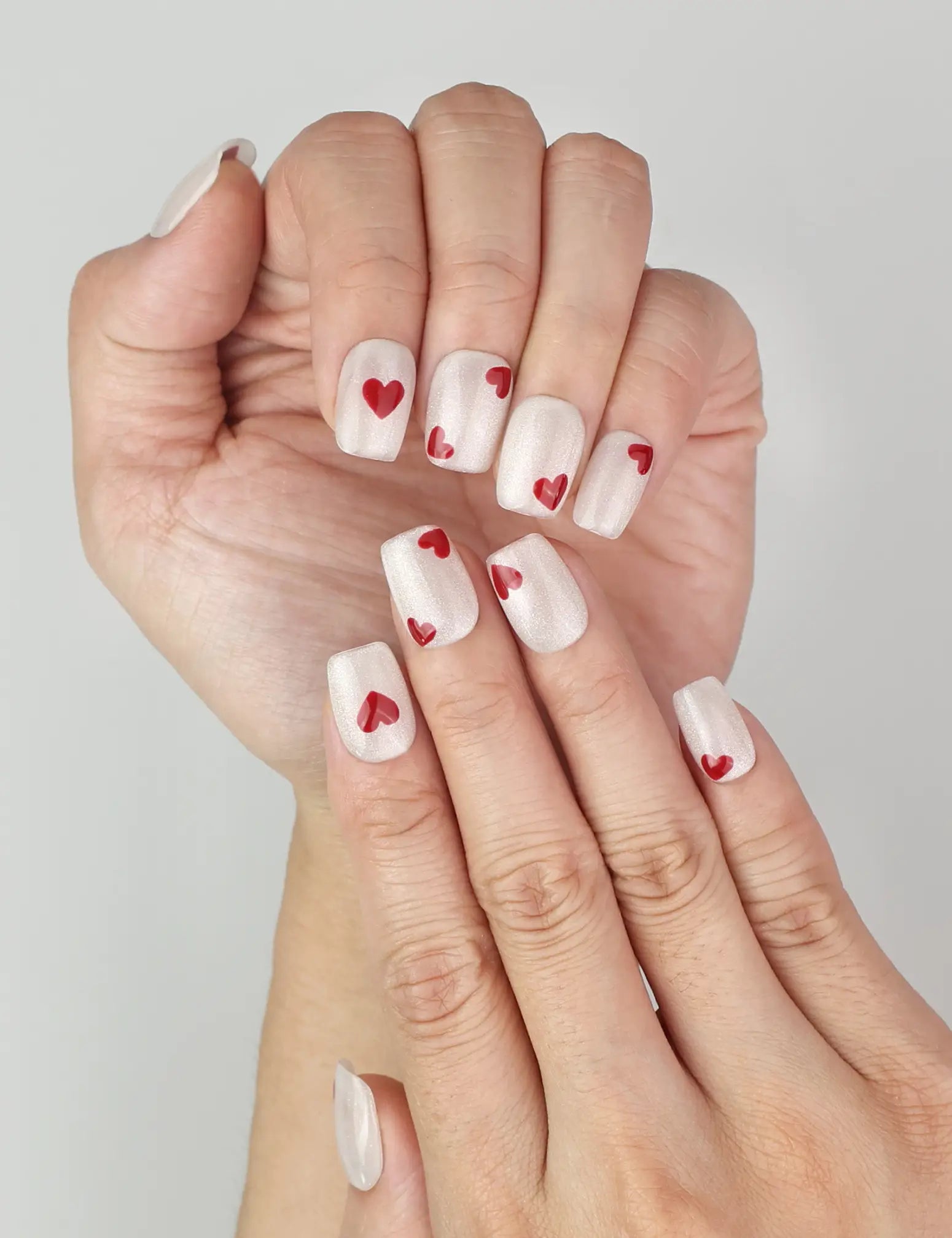 Close-up of naillover handmade Sparkle Love press on nails, sparkling white finish with romantic red hearts, trendy nails in Singapore.