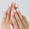 Hand model showing short coffin-shaped pink glitter press-on nails with 3D starfish charms in vibrant summer tones