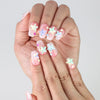 Close-up of Naillover pink press-on nails in glitter finish, featuring playful 3D starfish in coral, aqua, and yellow