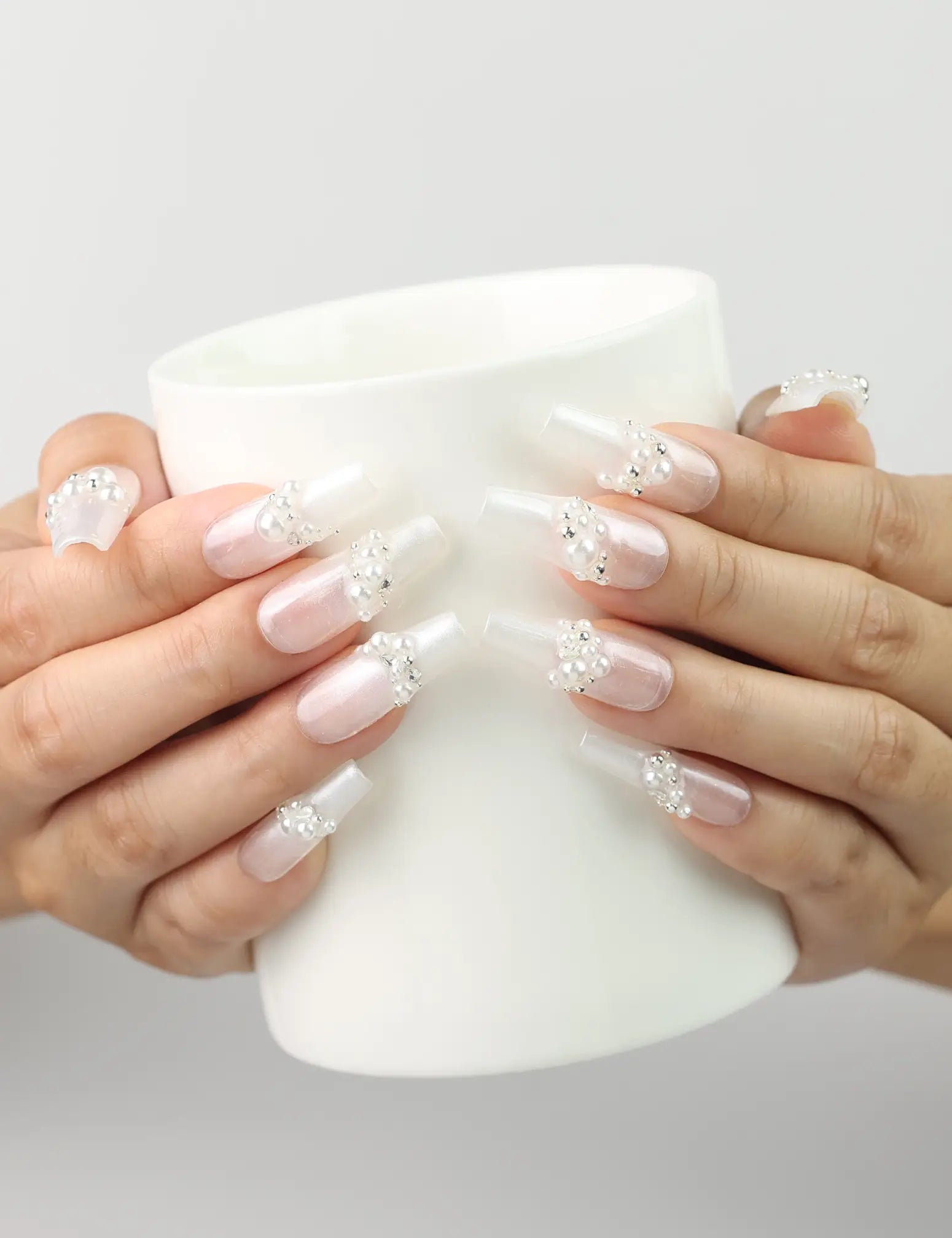 Woman holding a glass while wearing Starlight Singapore press on nails with white base and silver stars