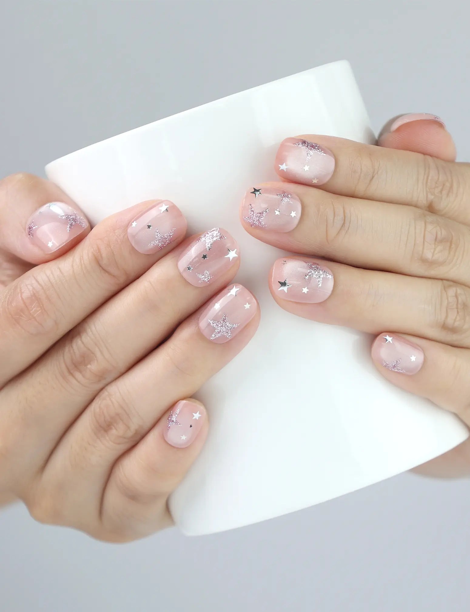 Woman holding a pastel mug while wearing Starlit Blush Singapore press on nails, showing cute and casual nail style.