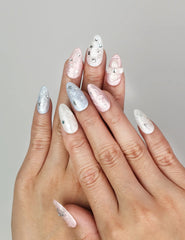 Hand wearing Naillover Starry Sweet Dream handmade press on nails in pearlescent pink, blue, and white with 3D stars and pearls.