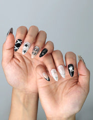 Side view of almond nails blending nude bases with bold black details and celestial-inspired nail art