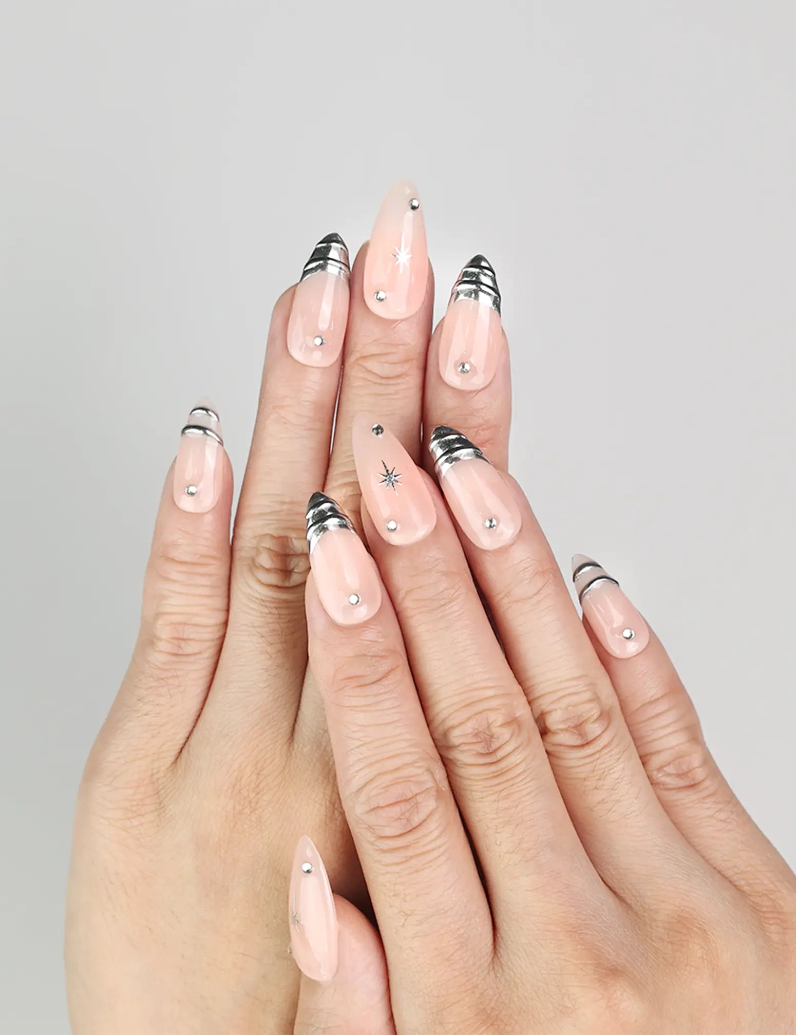 Hand model wearing Subtle Spark handmade Singapore press on nails in peach with silver stars