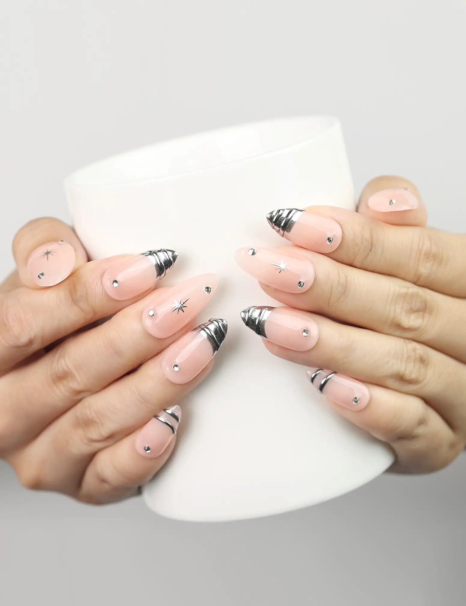 Subtle Spark handmade Singapore press on nails in peach with silver stars, holding a coffee cup