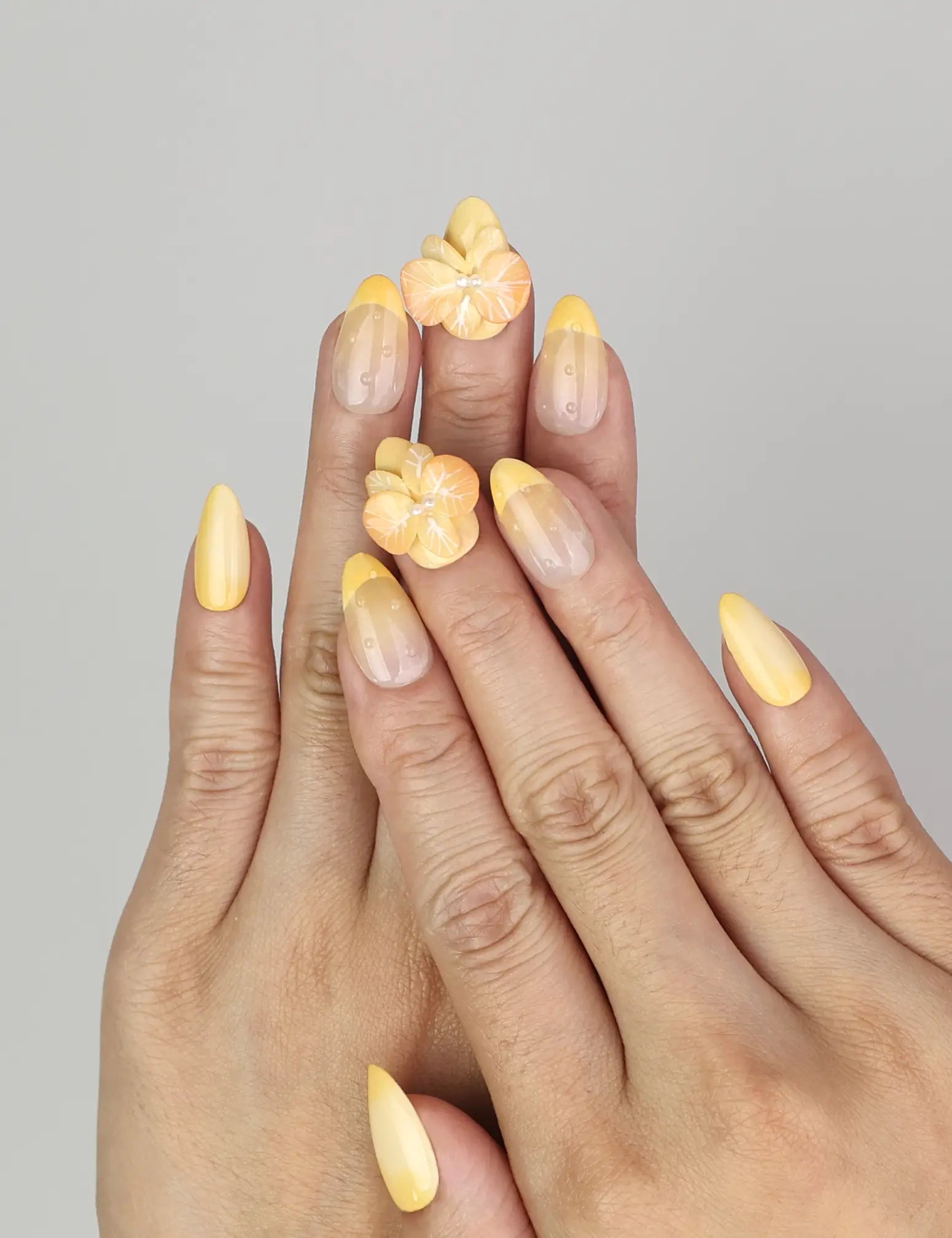 Hand wearing Naillover Sunny Bloom handmade press on nails with yellow-to-white gradient and 3D flower pearl detail.