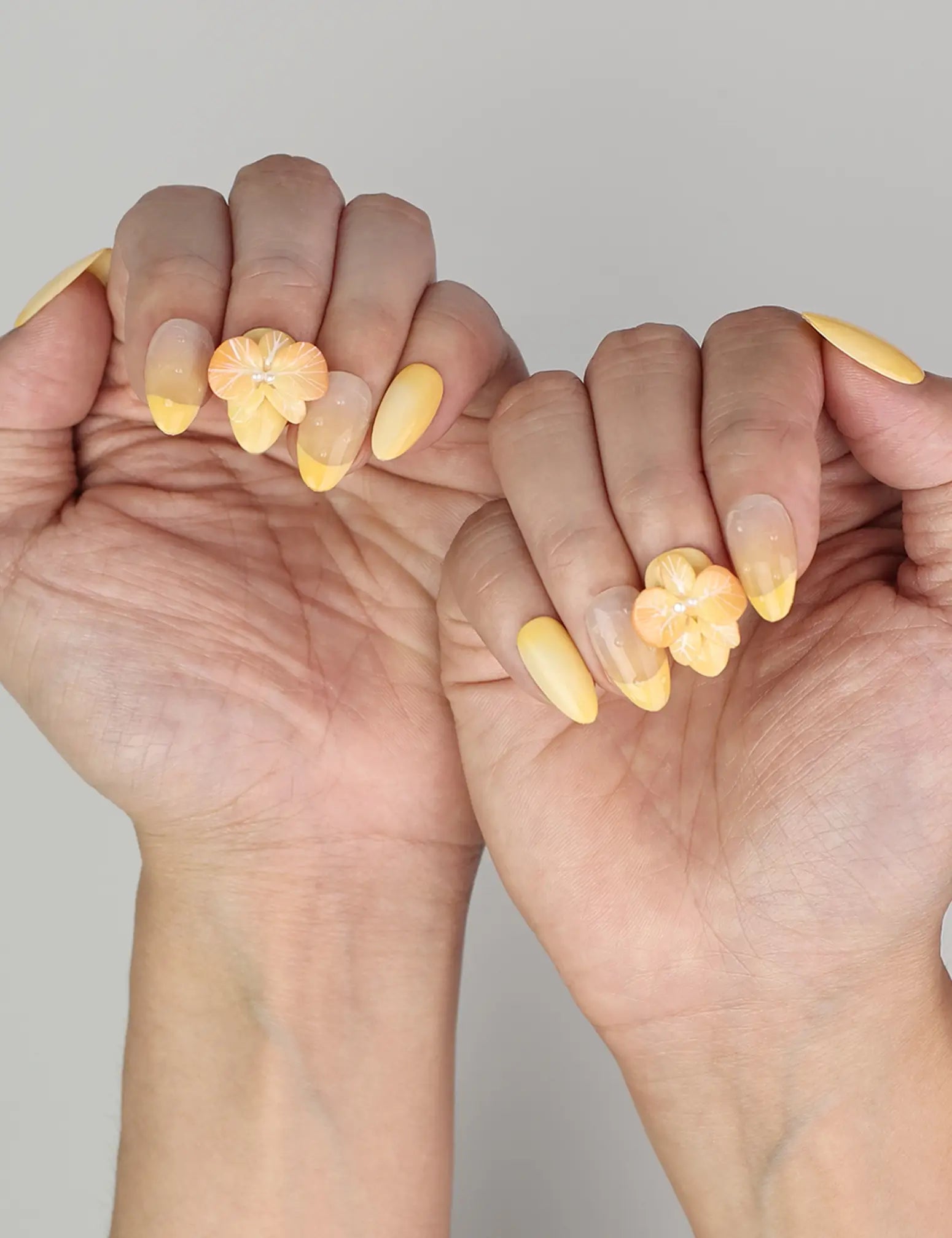 Naillover Sunny Bloom trendy nails styled on hand, featuring gradient yellow base with flower design.