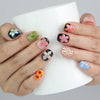 Hand holding a cup while wearing Naillover’s nude and black squoval nails adorned with 3D pink floral designs