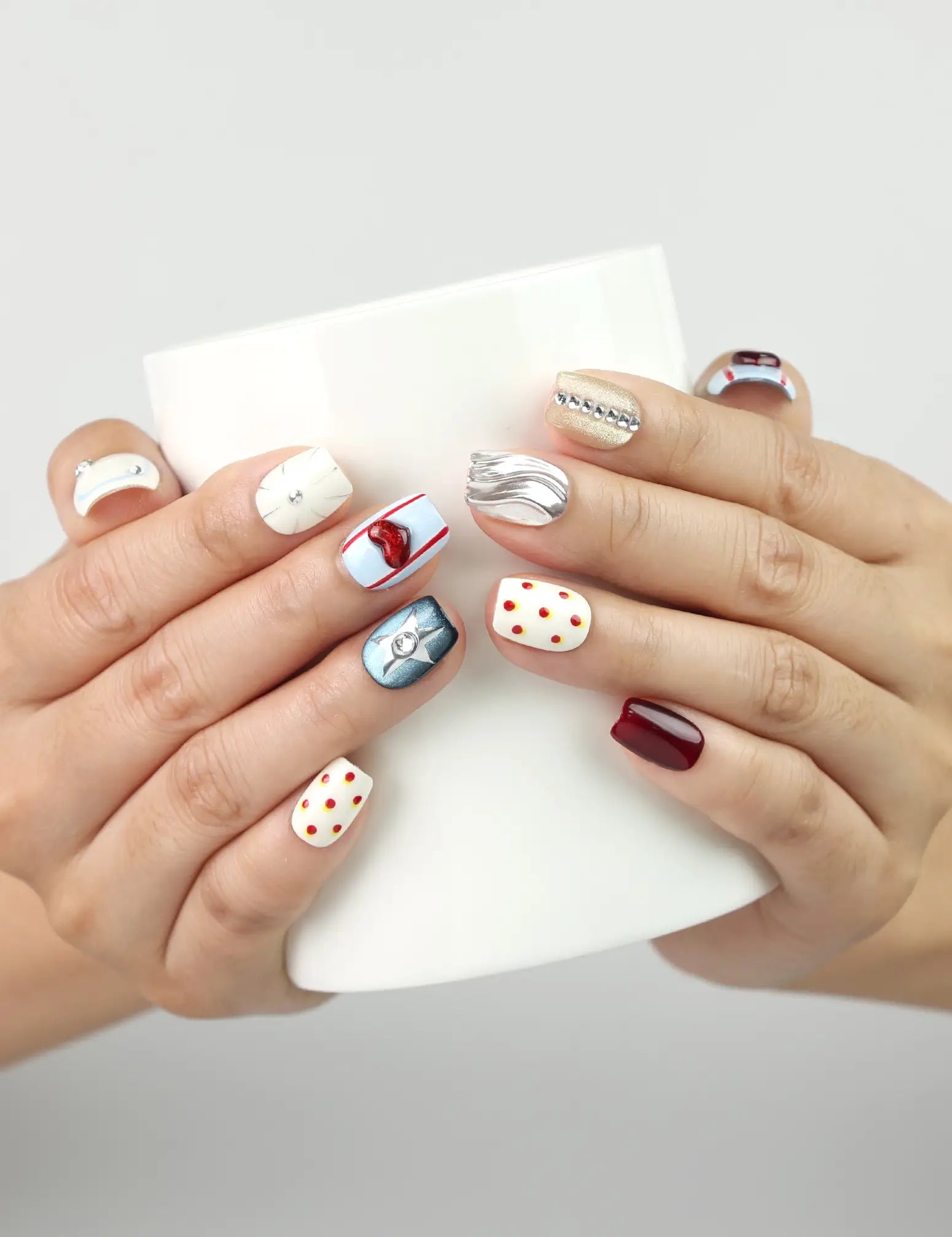Vibrant Pop Singapore press-on nails holding a coffee cup, showcasing red lips and silver button nail art.