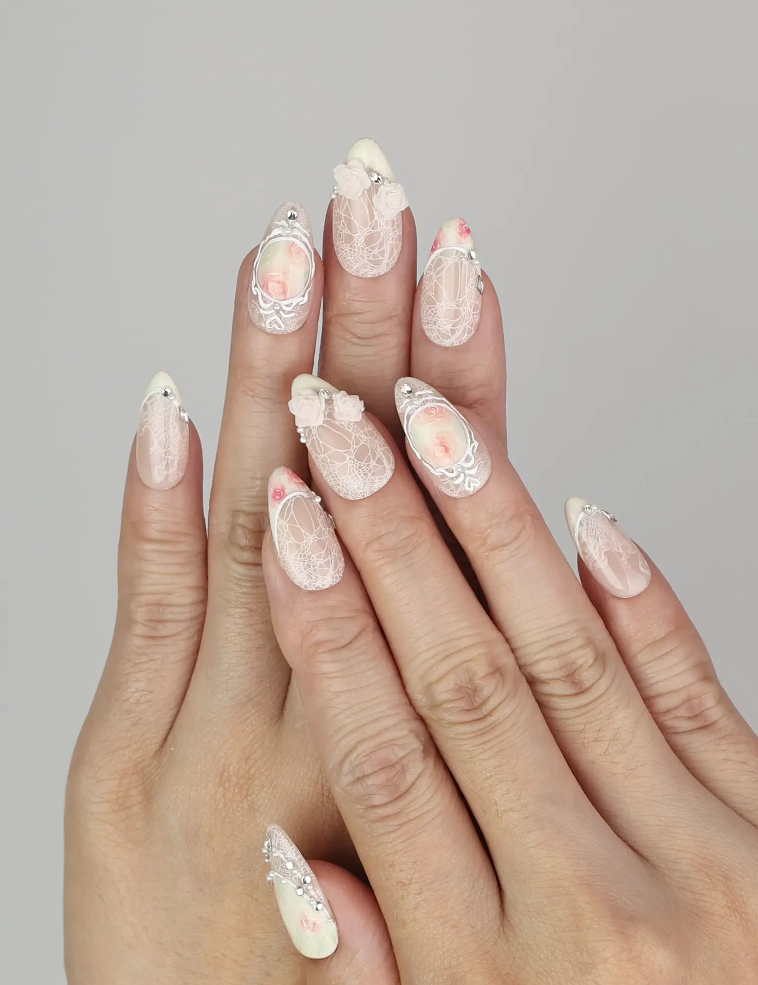 Hand wearing Naillover Vintage Rose Lace handmade press on nails with hand-painted roses and lace details.