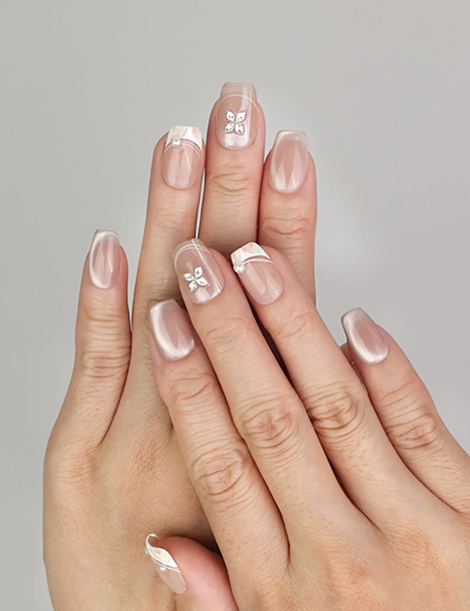 Hand wearing Naillover Whisper Beige handmade press on nails with sheer-to-nude gradient and silver gemstone accent.