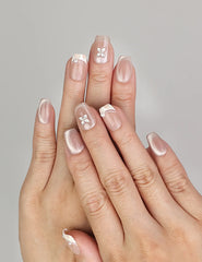 Hand wearing Naillover Whisper Beige handmade press on nails with sheer-to-nude gradient and silver gemstone accent.