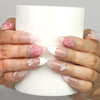 Hand holding a cup while wearing Naillover Whispering Petals in Pink Haze handmade press on nails with pink flowers and butterfly accents.