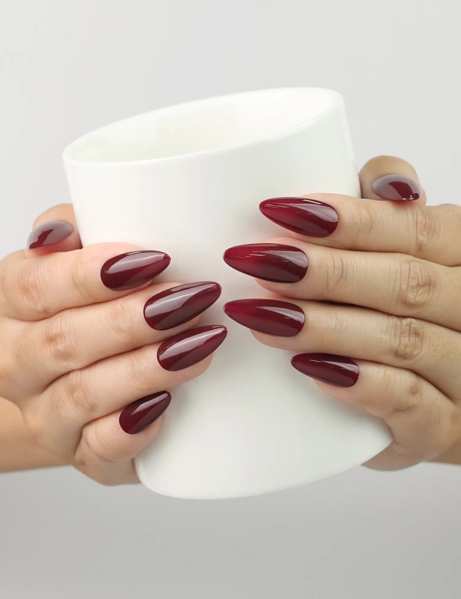 Model holding a wine glass while wearing Wine Velvet deep red almond Singapore press on nails by Naillover, creating a refined, classic vibe.