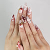 Model wearing Xmas Sparkle red and white press-on nails with festive bows, handmade Singapore nails by naillover