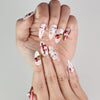 Close-up of Xmas Sparkle red and white press-on nails with bow accents, Singapore handmade nails by naillover