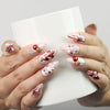 Hand holding a cup wearing Xmas Sparkle red and white handmade press-on nails with festive bows, Singapore nails by naillover